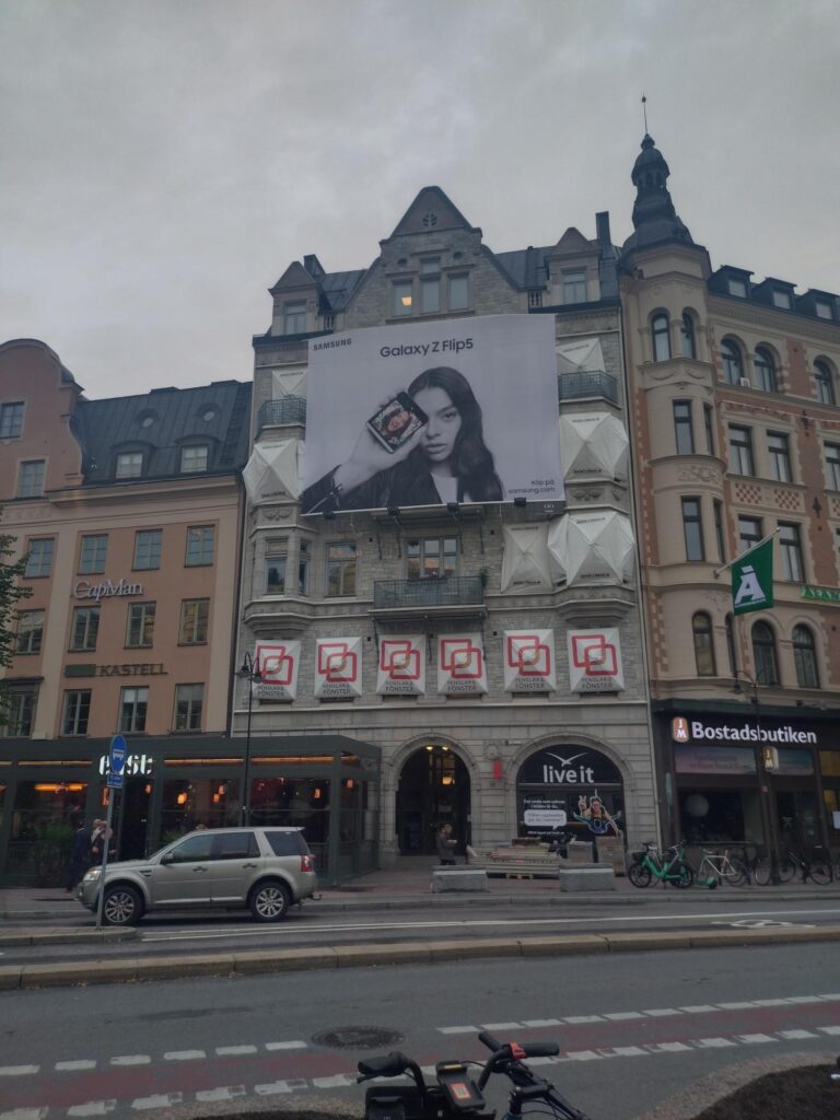 Fönsterparaply monterat på en byggnad med reklam för Samsung